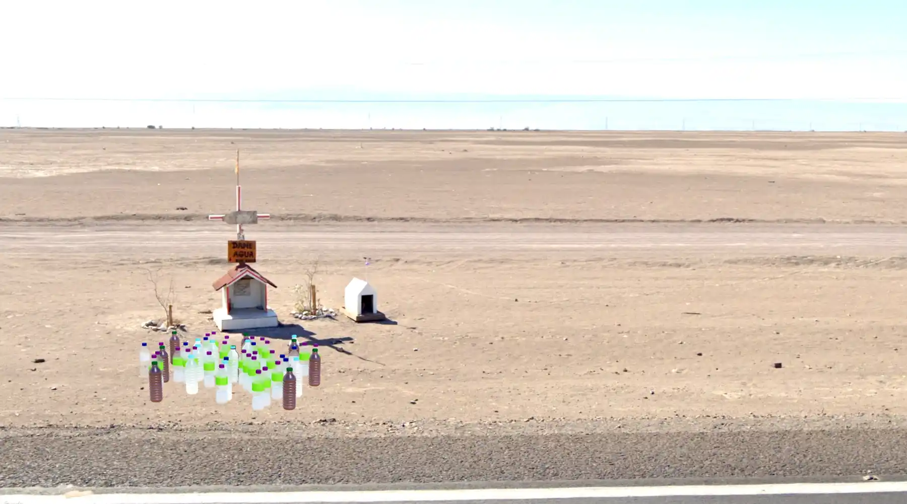 An animita in Google Street View with 3D models of bottles in front of it. The sign on the animita says 'Dame agua'.